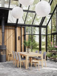 Photorealistic 3D visualization of a winter garden with glass walls, featuring a dining table and chairs in a light-filled interior, created by Nordic Render.